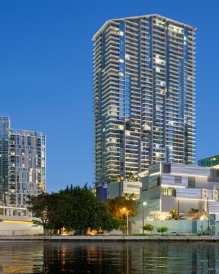 High-rise architecture at Brickell City Centre by Arquitectonica, with balconies, trees along the waterfront and reflections under a blue daytime sky.
