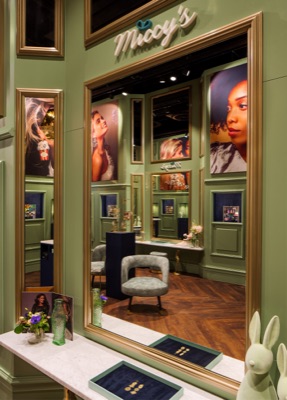 Miccy’s interior with green wall panels, gold-coloured mirror frames, jewellery displays, model portraits and an armchair on a wooden herringbone floor.