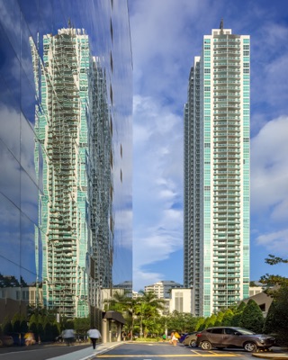 Skyscraper and its reflection in a mirrored glass building facade at Plaza On Brickell, with street, trees, and cars below.